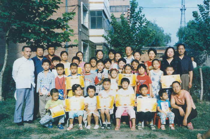 2002年暑期彭飞先生（左一）与涿州文昌祠小区领导和《三字经》学习班学员的义教结课合影）